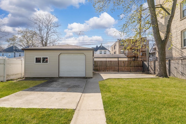 detached garage featuring fence and concrete driveway