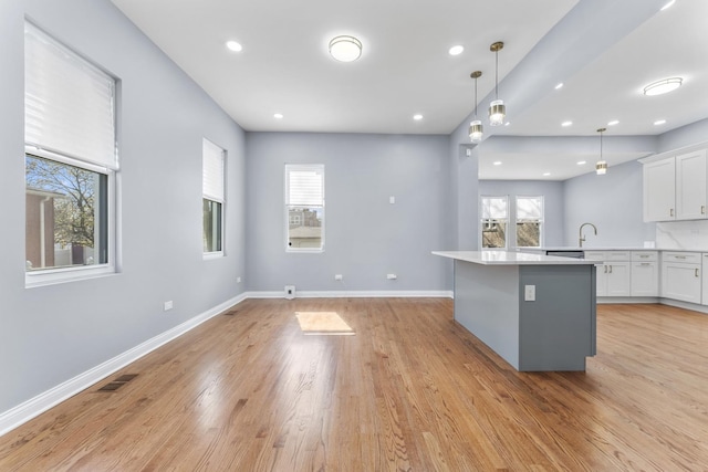 kitchen featuring hanging light fixtures, light wood-style flooring, light countertops, white cabinetry, and visible vents
