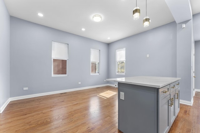 kitchen featuring baseboards, hanging light fixtures, a kitchen island, light wood finished floors, and gray cabinetry