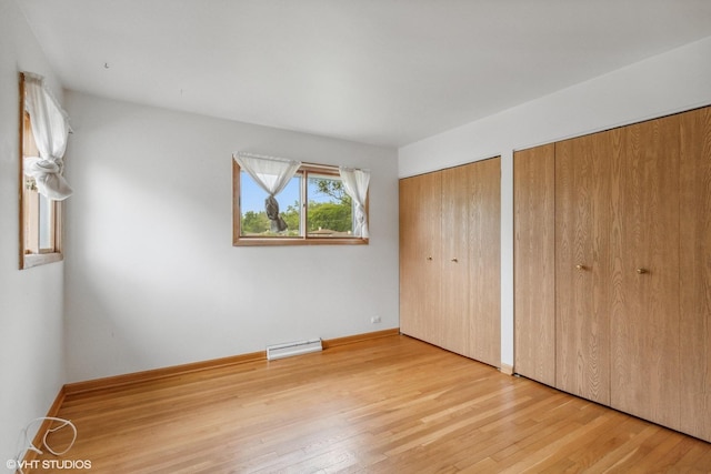 116 E Armitage Ave, Addison, IL 60101 - unfurnished bedroom featuring multiple closets, light wood-type flooring, baseboards, and a baseboard radiator