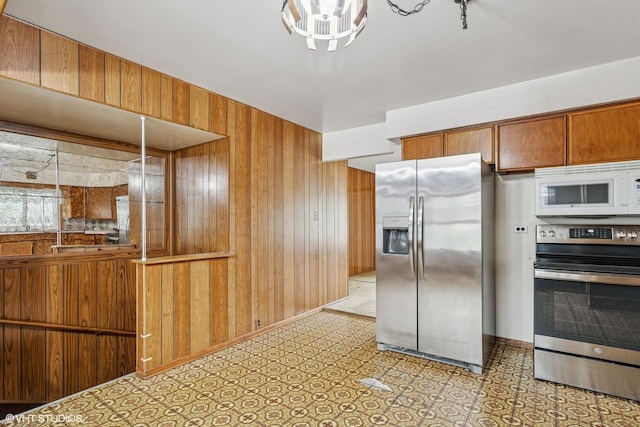 116 E Armitage Ave, Addison, IL 60101 - kitchen featuring stainless steel appliances, wooden walls, brown cabinetry, and baseboards
