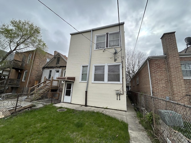 rear view of house featuring a lawn and fence