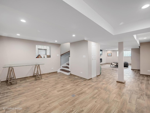 basement featuring recessed lighting, baseboards, light wood finished floors, and stairs