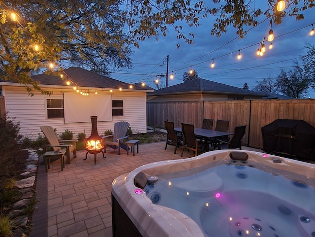 view of patio with a fire pit, fence, area for grilling, a hot tub, and outdoor dining space