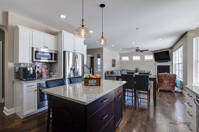 dining room with baseboards, dark wood-style flooring, a lit fireplace, and recessed lighting