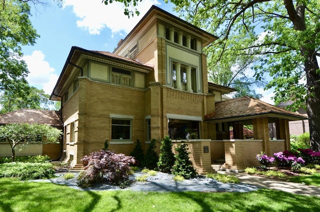 rear view of property with brick siding and a lawn
