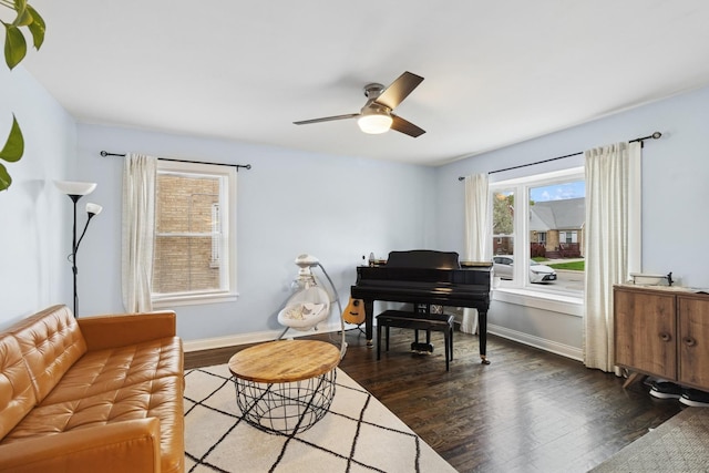 living area with baseboards, a ceiling fan, and dark wood-style flooring