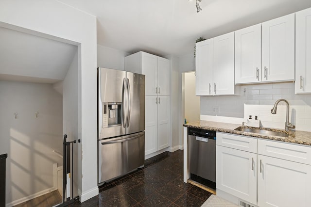 kitchen with backsplash, a sink, baseboards, white cabinets, and stainless steel appliances