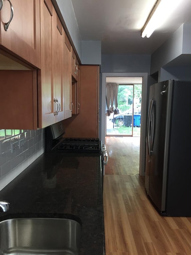 1428 E 55th St, Chicago, IL 60615 - kitchen featuring freestanding refrigerator, dark countertops, brown cabinets, light wood-style flooring, and backsplash