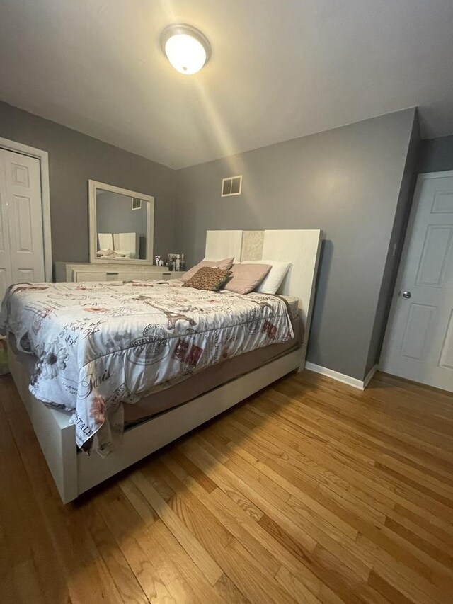bedroom featuring baseboards, light wood-type flooring, and visible vents