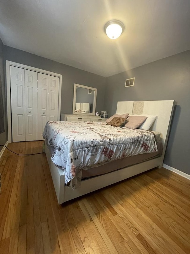 bedroom featuring visible vents, baseboards, a closet, and hardwood / wood-style floors