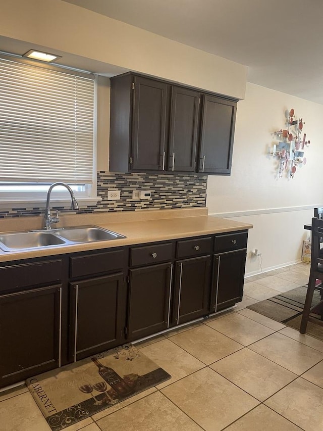 kitchen featuring light countertops, light tile patterned flooring, decorative backsplash, and a sink