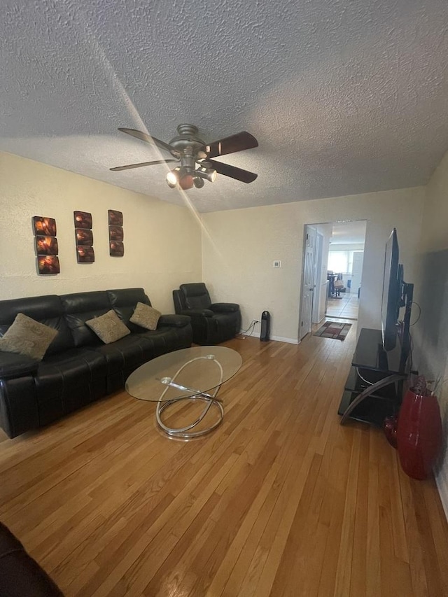 living area featuring a ceiling fan, a textured ceiling, and hardwood / wood-style flooring