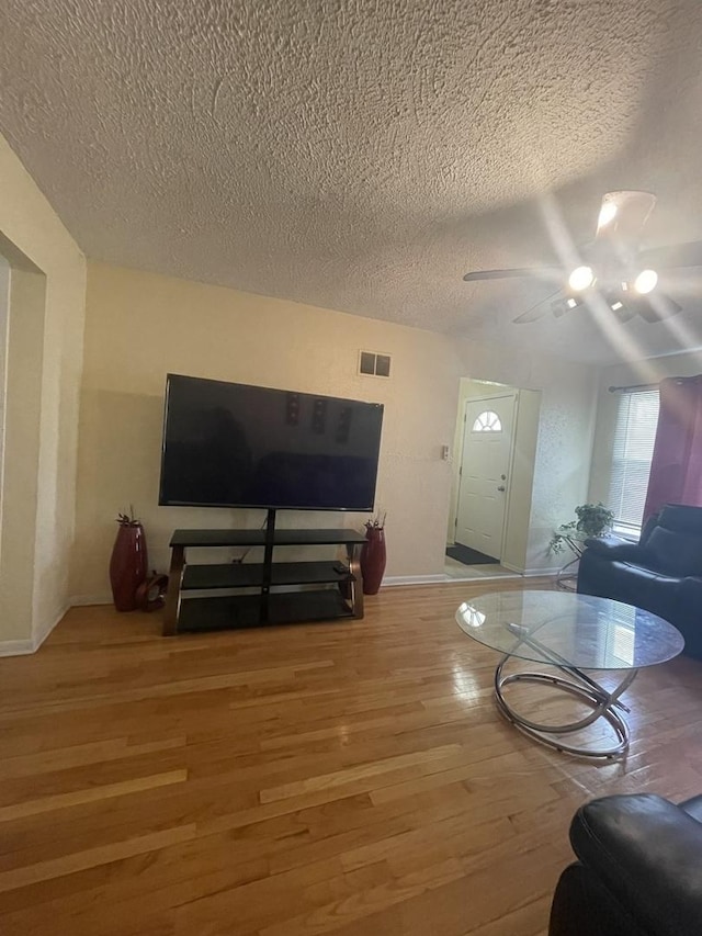 living area featuring a textured ceiling, visible vents, and light wood-type flooring