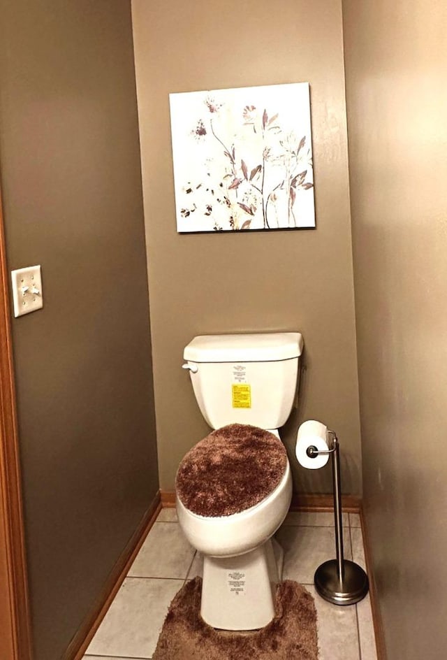 bathroom featuring baseboards, tile patterned floors, and toilet