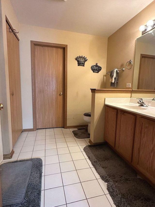 bathroom featuring toilet, baseboards, tile patterned flooring, and vanity