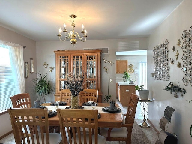 dining area with an inviting chandelier, light carpet, and a healthy amount of sunlight