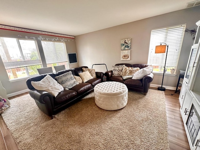 living area with visible vents, light wood finished floors, and baseboards