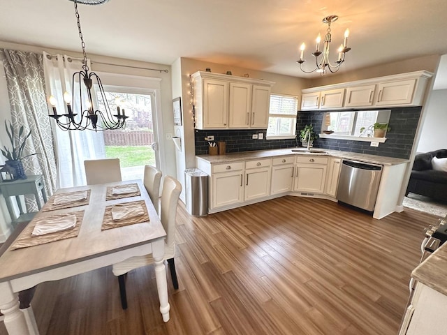 kitchen with an inviting chandelier, decorative backsplash, hanging light fixtures, and stainless steel dishwasher