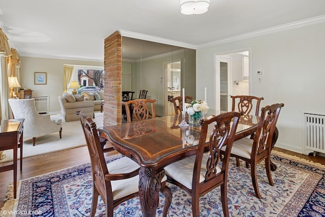 dining area featuring crown molding, baseboards, wood finished floors, and radiator heating unit