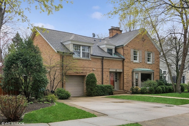 view of front of house with driveway, a chimney, brick siding, a front lawn, and an attached garage