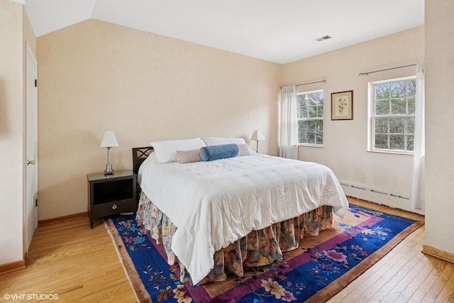 bedroom featuring light wood-type flooring, a baseboard radiator, baseboards, and visible vents