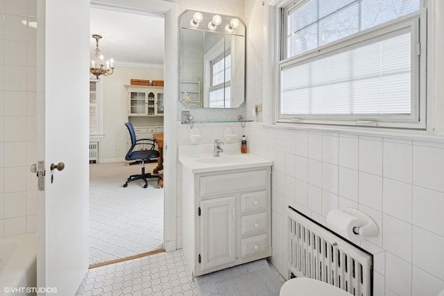 bathroom with vanity, ornamental molding, a bathtub, and a chandelier
