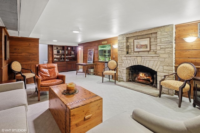 living room with a stone fireplace, wooden walls, and light colored carpet