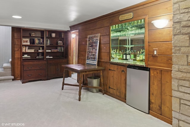 bar featuring bar area, fridge, and wood walls