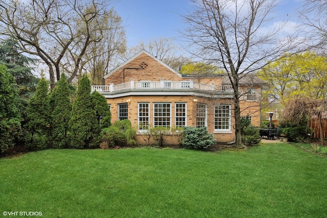 rear view of property featuring a yard, brick siding, and a balcony