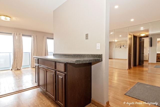 kitchen with recessed lighting, dark countertops, dark brown cabinetry, and light wood-style flooring