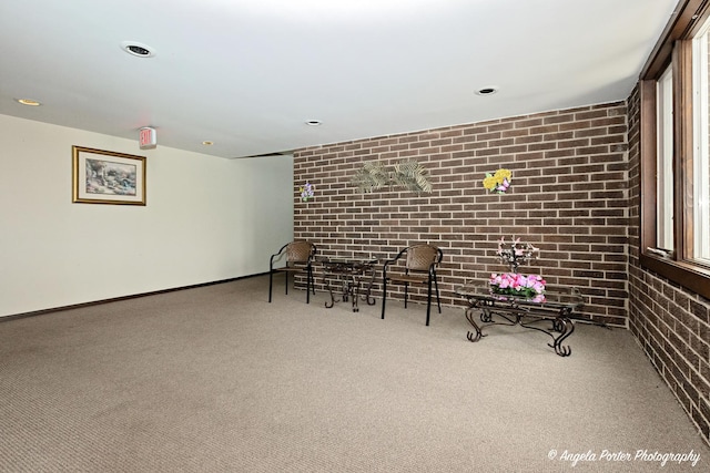 sitting room featuring carpet floors, baseboards, recessed lighting, and brick wall