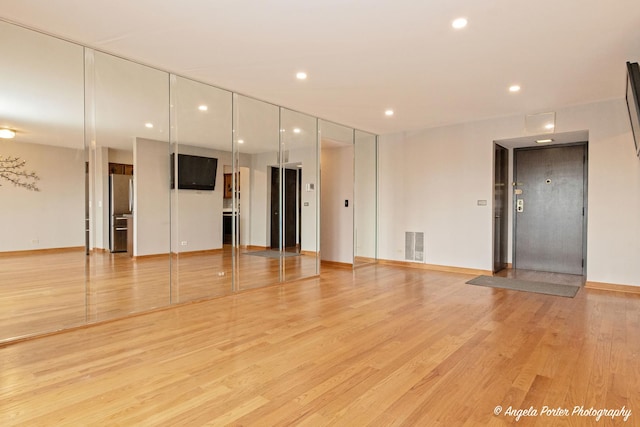 unfurnished living room with light wood-style floors, baseboards, recessed lighting, and visible vents