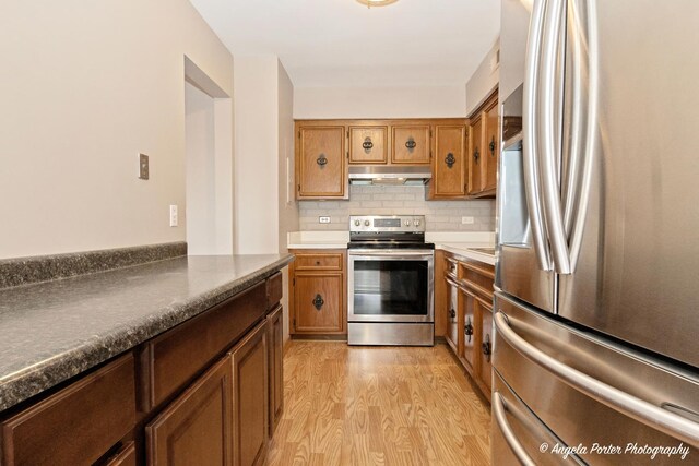 kitchen featuring light wood-style floors, appliances with stainless steel finishes, under cabinet range hood, and brown cabinets