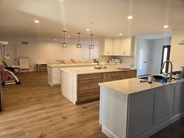 kitchen with a spacious island, recessed lighting, white cabinets, and a sink