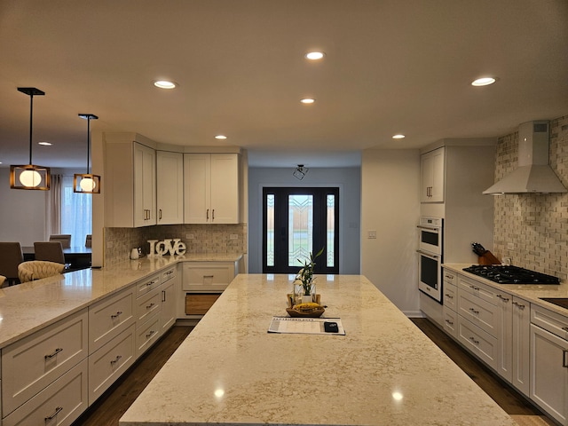 kitchen with stainless steel double oven, recessed lighting, wall chimney exhaust hood, black gas cooktop, and backsplash