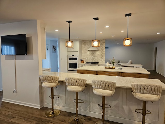 kitchen featuring recessed lighting, white double oven, a kitchen island, baseboards, and dark wood-type flooring