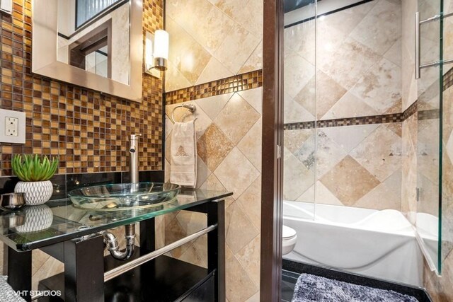 bathroom with backsplash, tile walls, vanity, toilet, and tub / shower combination