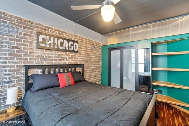 bedroom with ceiling fan and brick wall
