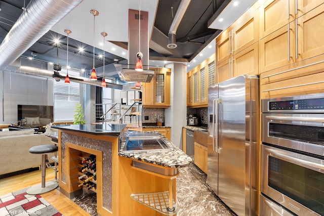 kitchen with appliances with stainless steel finishes, light wood finished floors, backsplash, open floor plan, and a kitchen island