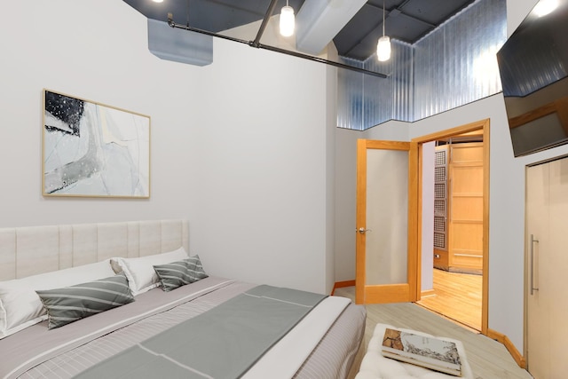bedroom featuring wood finished floors and a towering ceiling