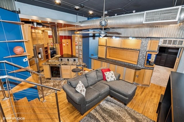 living room featuring wine cooler, bar area, light wood-style flooring, and visible vents