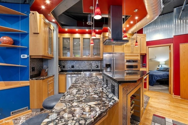 kitchen featuring backsplash, appliances with stainless steel finishes, light wood-type flooring, a sink, and dark stone countertops