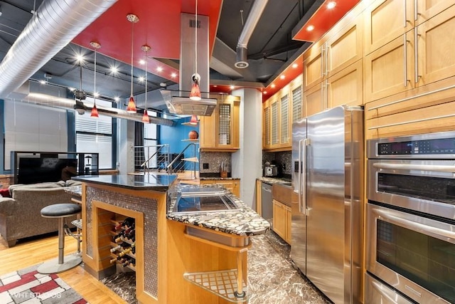 kitchen featuring backsplash, a kitchen island, appliances with stainless steel finishes, open floor plan, and light wood-style flooring