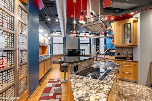kitchen featuring dark countertops, backsplash, a kitchen island, and black electric cooktop