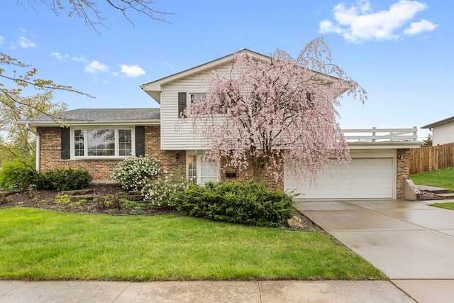 split level home featuring brick siding, a front yard, and concrete driveway