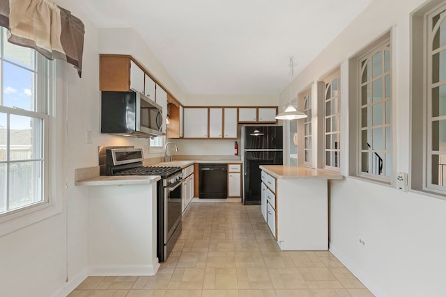 kitchen with light countertops, a sink, a healthy amount of sunlight, and black appliances