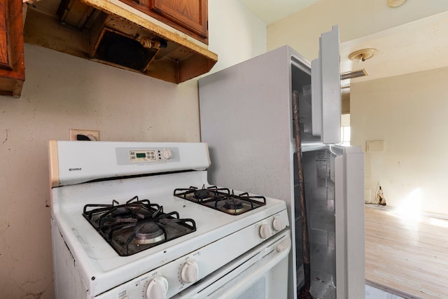 14533 Ashland Ave, Harvey, IL 60426 - kitchen featuring white gas range, brown cabinetry, and under cabinet range hood