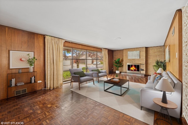 living room with visible vents, wooden walls, and a fireplace