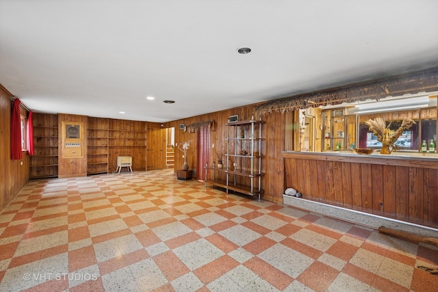 interior space featuring baseboards, wood walls, recessed lighting, and built in shelves